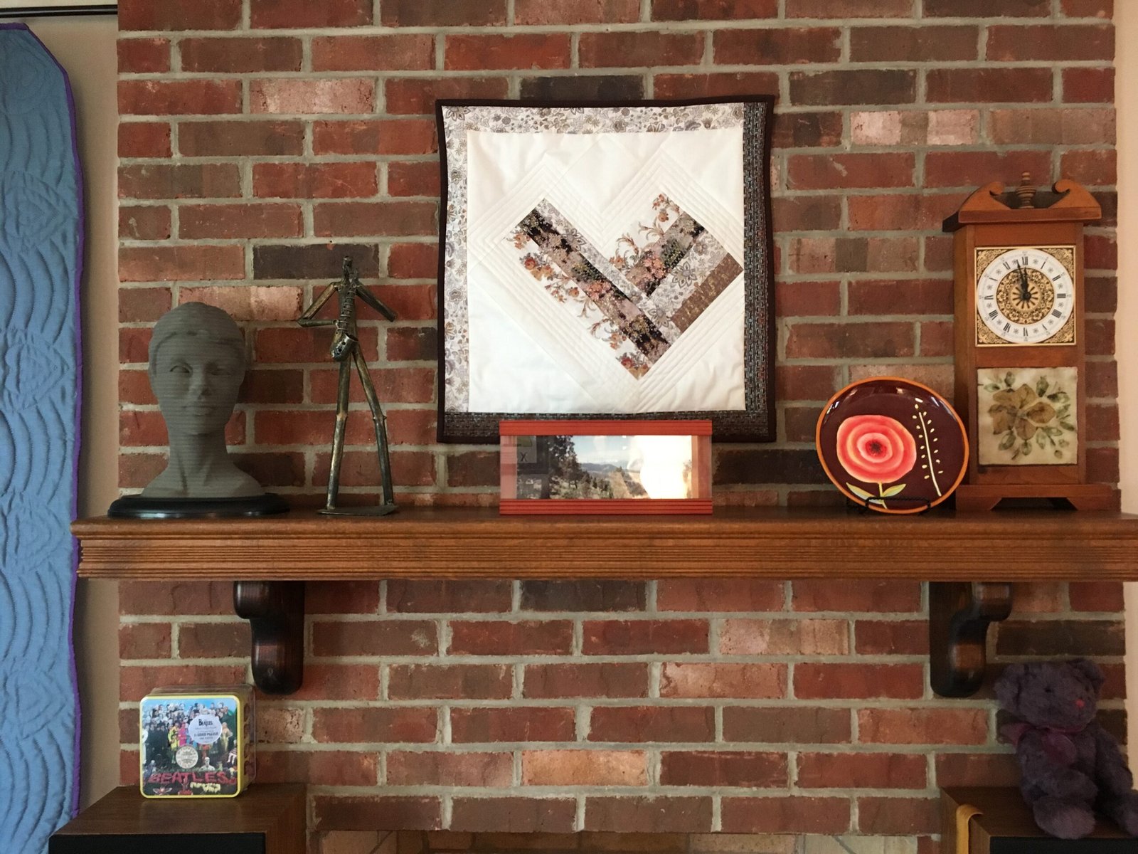 Floating 'L' wall hanging on brick wall above fireplace
